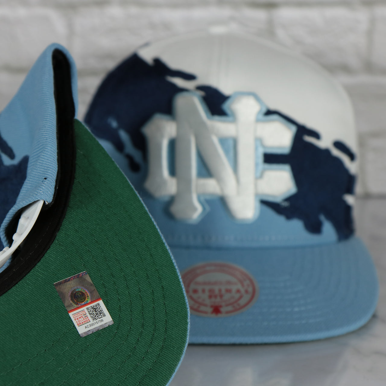 green under visor on the University of North Carolina Tar Heels Vintage Retro Paintbrush Mitchell and Ness Snapback Hat | White/Blue