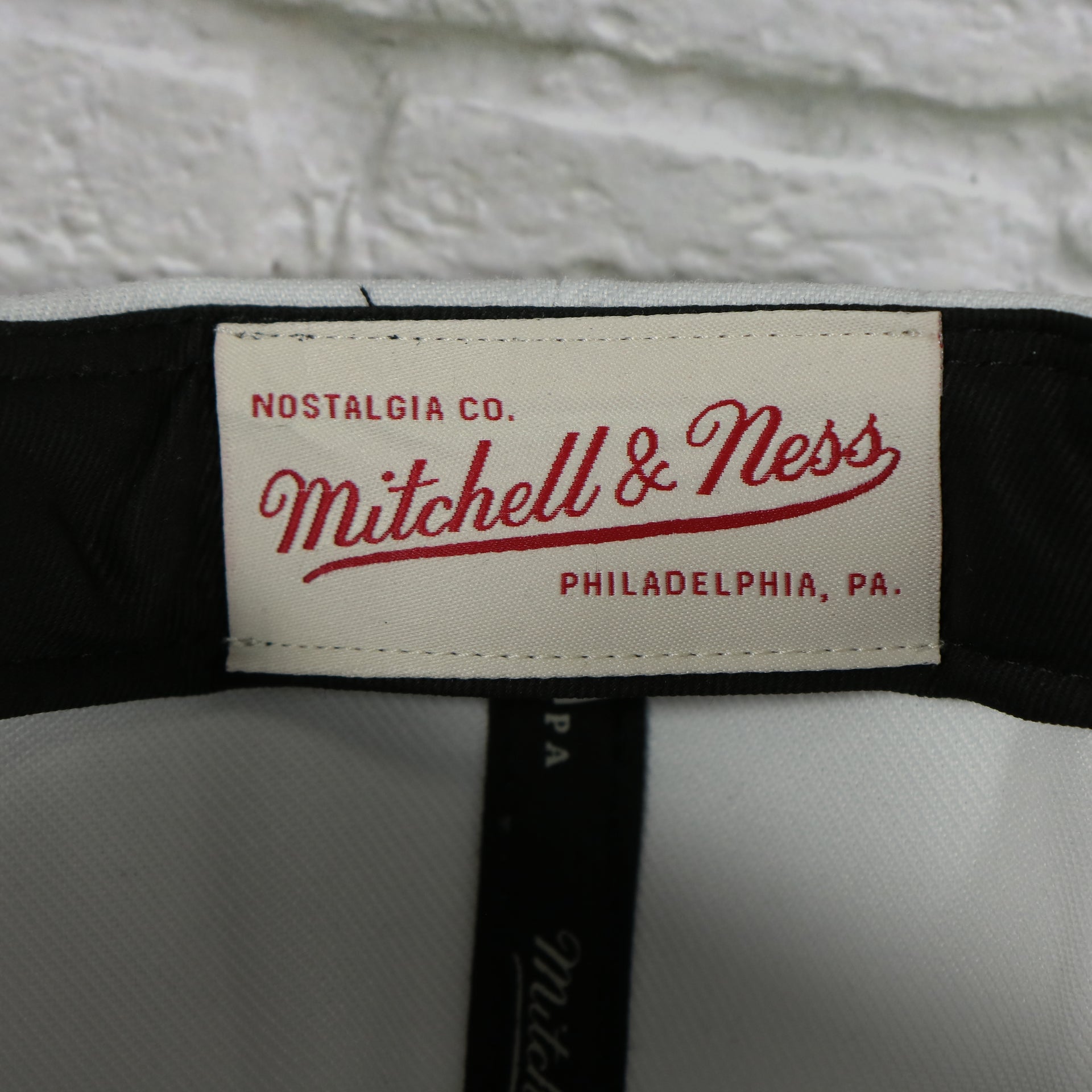 mitchell and ness label on the University of North Carolina Tar Heels Vintage Retro Paintbrush Mitchell and Ness Snapback Hat | White/Blue
