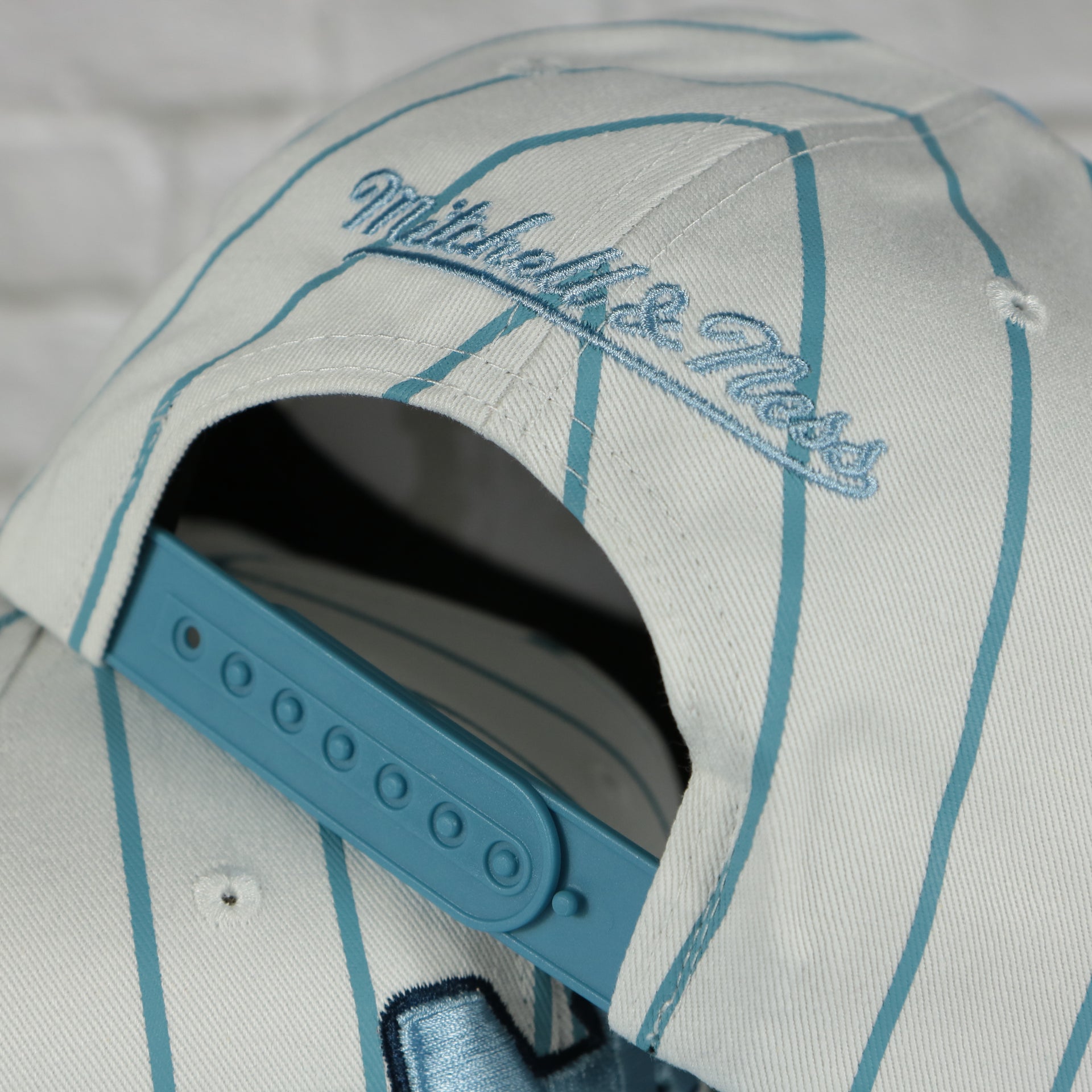 mitchell and ness logo on the University of North Carolina Tar Heels Vintage Pinstripe Baseball Hat | Retro Mitchell and Ness White Pinstripe Snapback Hat