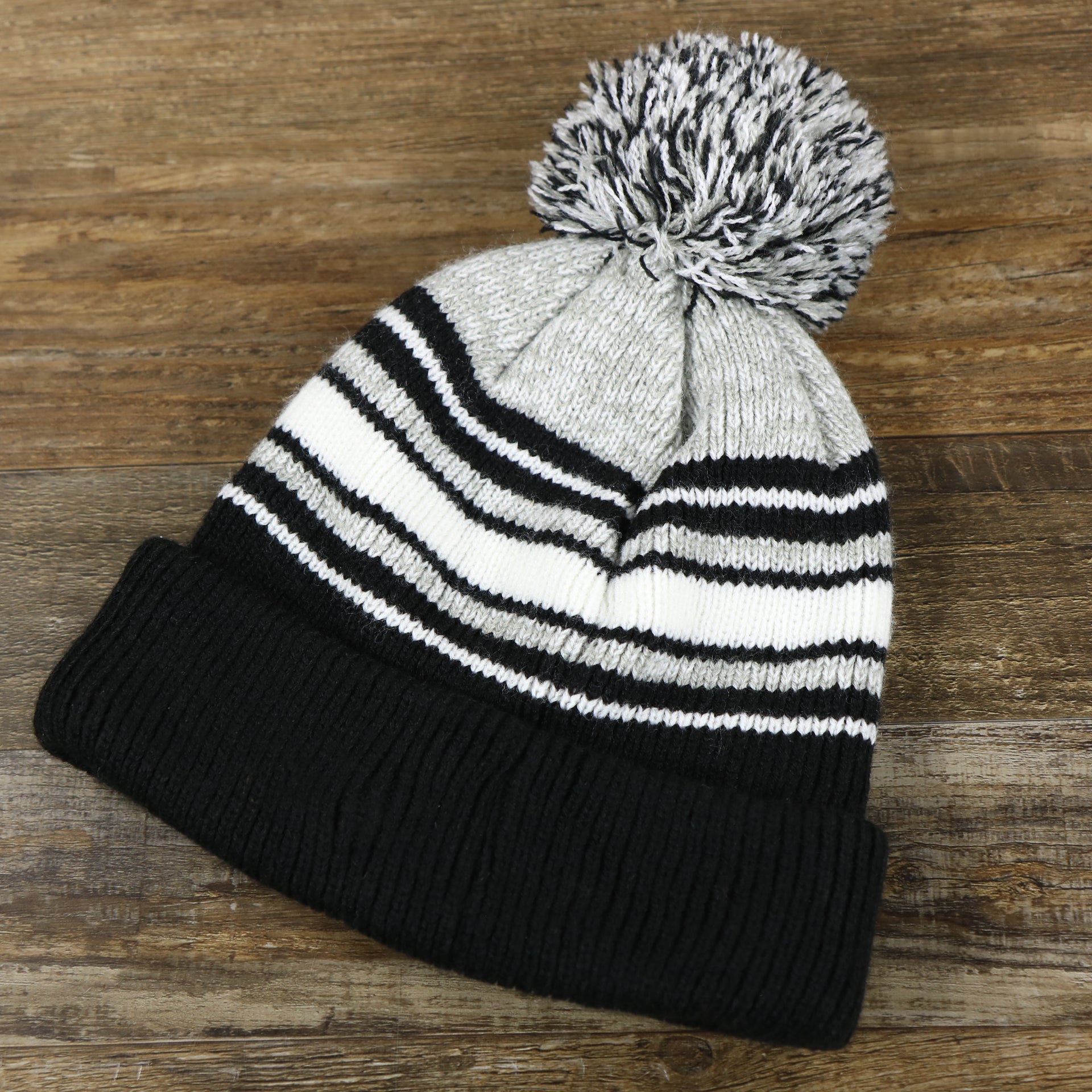 back side of the Kid’s Oakland Raiders Striped Cuffed Winter Beanie With Pom Pom | Kid’s  Black And Gray Winter Beanie
