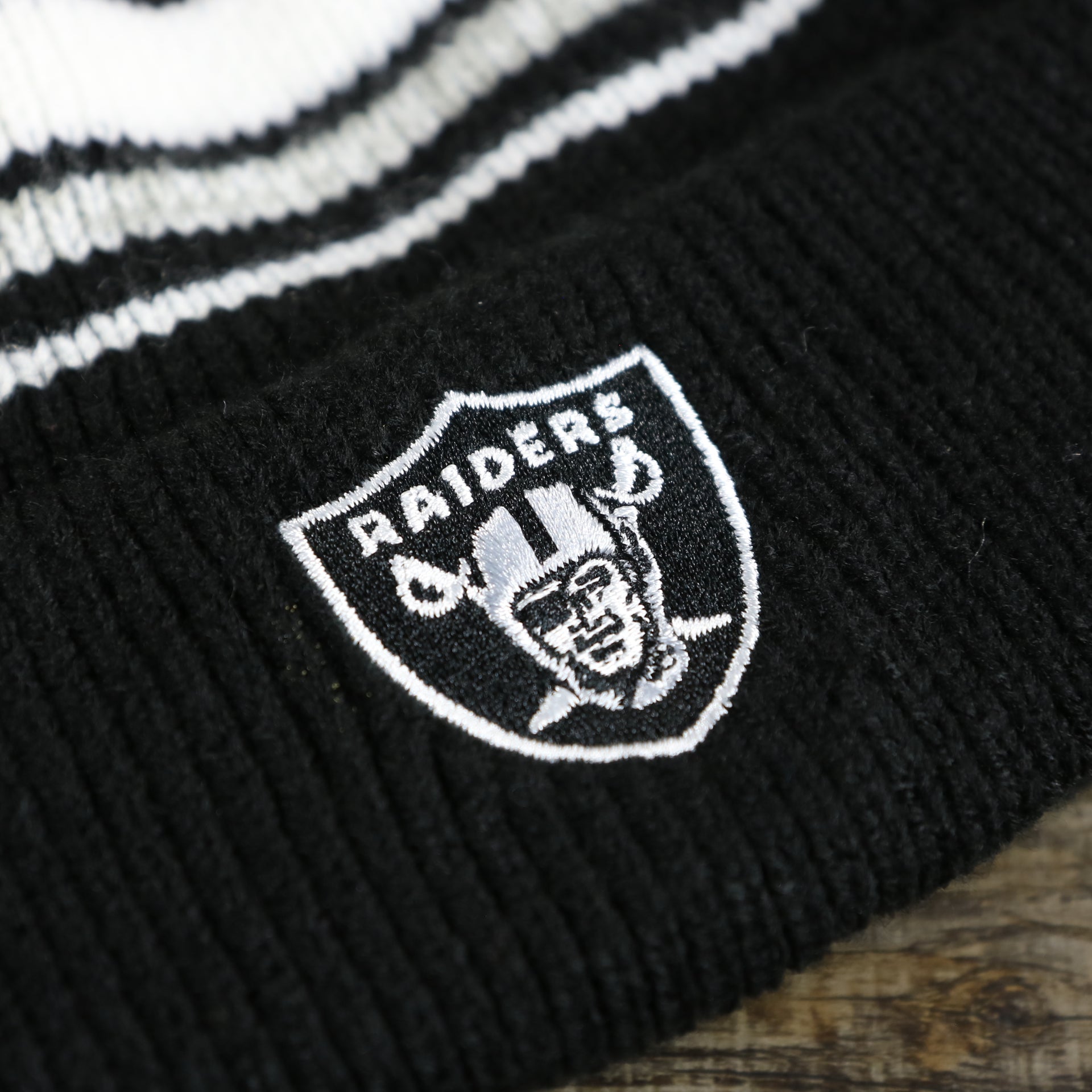 raiders logo on the Kid’s Oakland Raiders Striped Cuffed Winter Beanie With Pom Pom | Kid’s  Black And Gray Winter Beanie