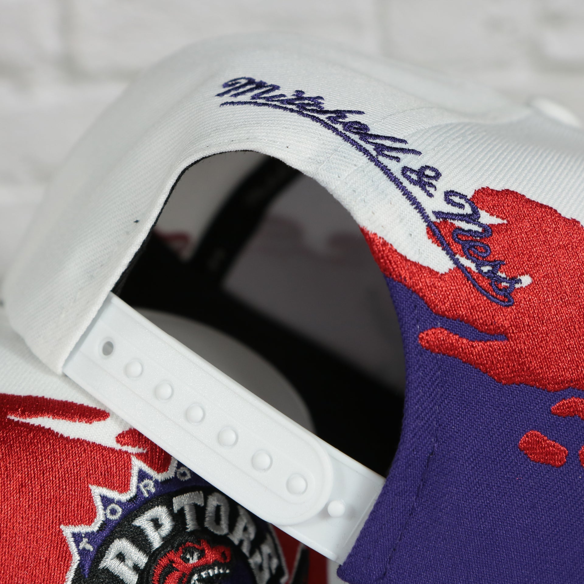 mitchell and ness logo on the Toronto Raptors Vintage Retro NBA Paintbrush Mitchell and Ness Snapback Hat | Purple/White/Red