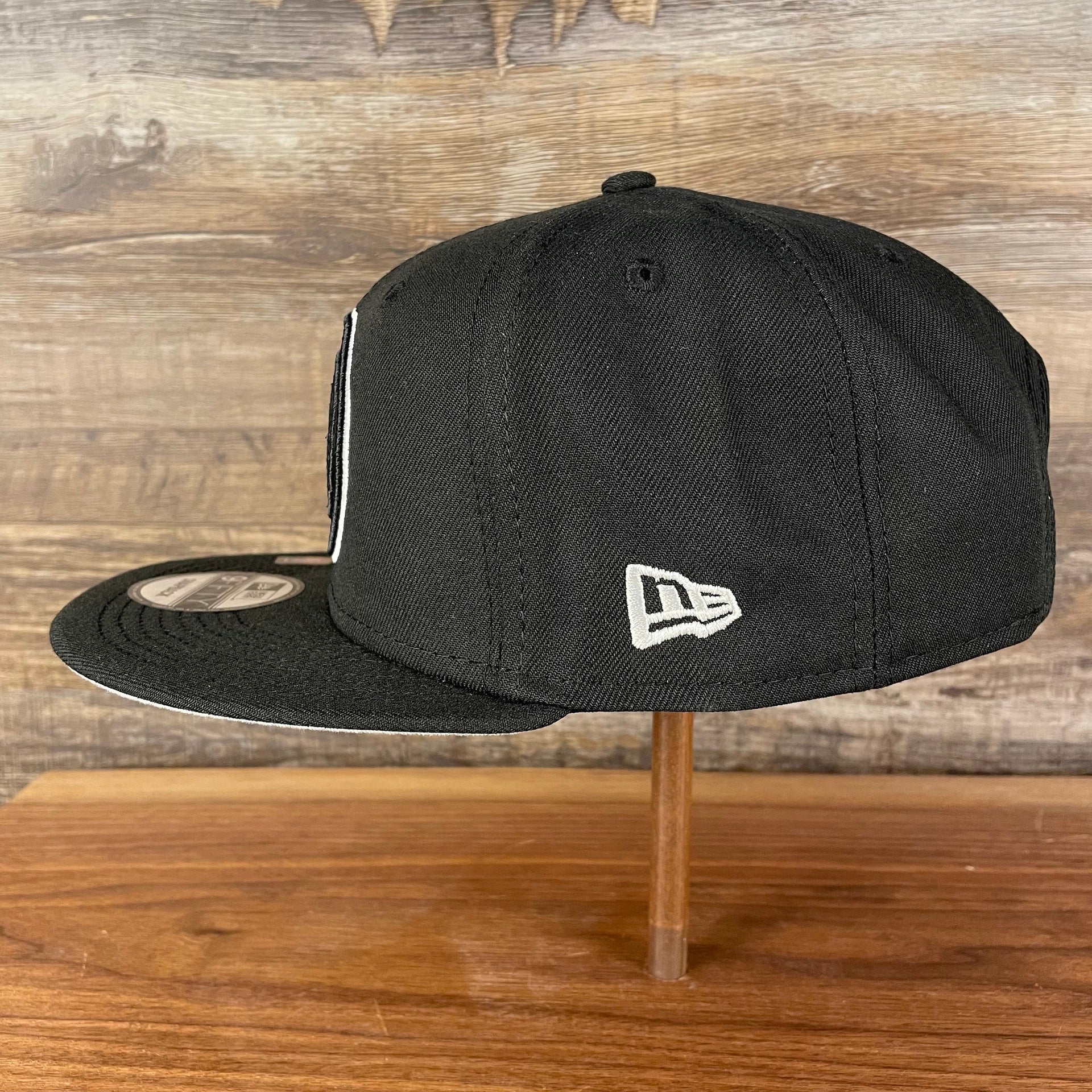 Wearer's left of the Brooklyn Nets NBA 75th Anniversary Side Patch Gray Bottom Black 9Fifty Snapback Hat | Back Half