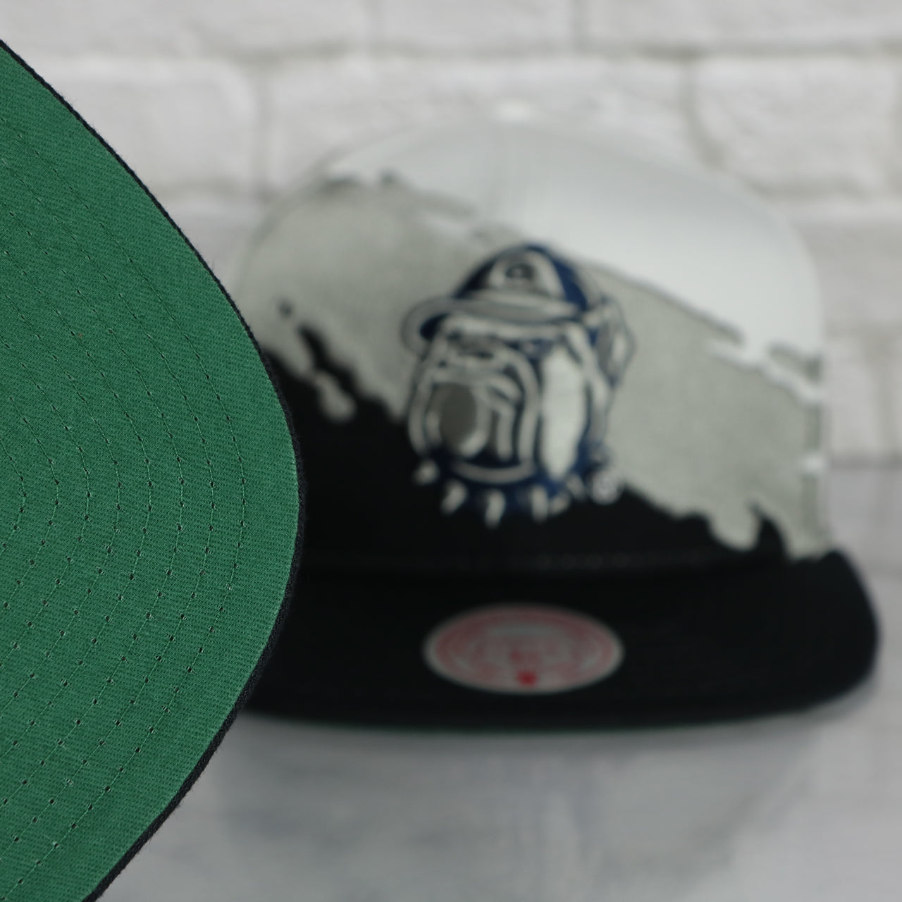 green under visor on the Georgetown University Hoyas Vintage Retro Paintbrush Mitchell and Ness Snapback Hat | White/Navy Blue/ Gray