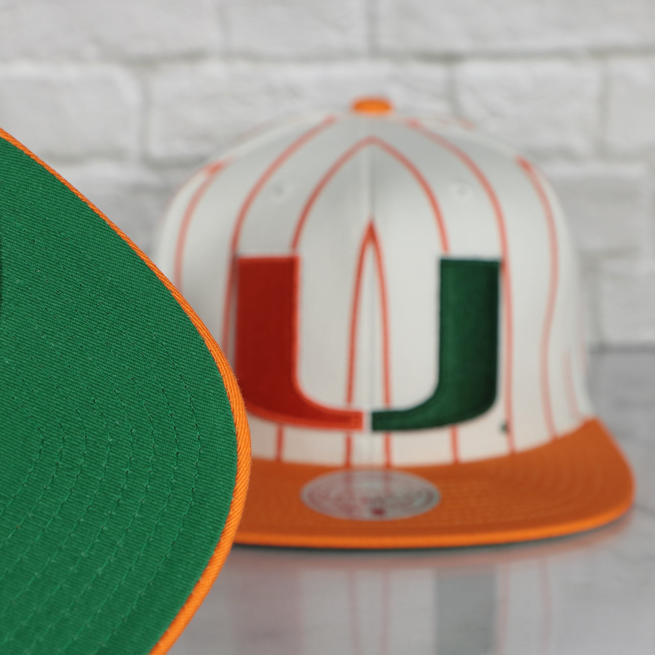 green under visor on the University of Miami Hurricanes Vintage Pinstripe Baseball Hat | Retro Mitchell and Ness White Pinstripe Snapback Hat