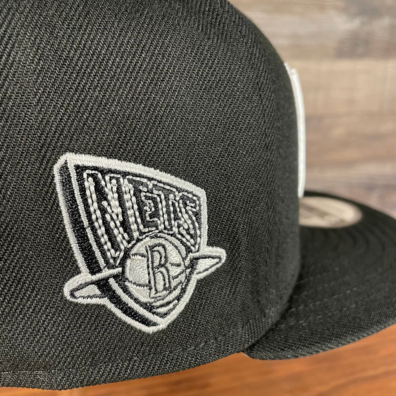 Close up of the retro 2012 side patch logo on the Brooklyn Nets NBA 75th Anniversary 2012 Side Patch Gray Bottom Black 9Fifty Snapback Hat | City Edition