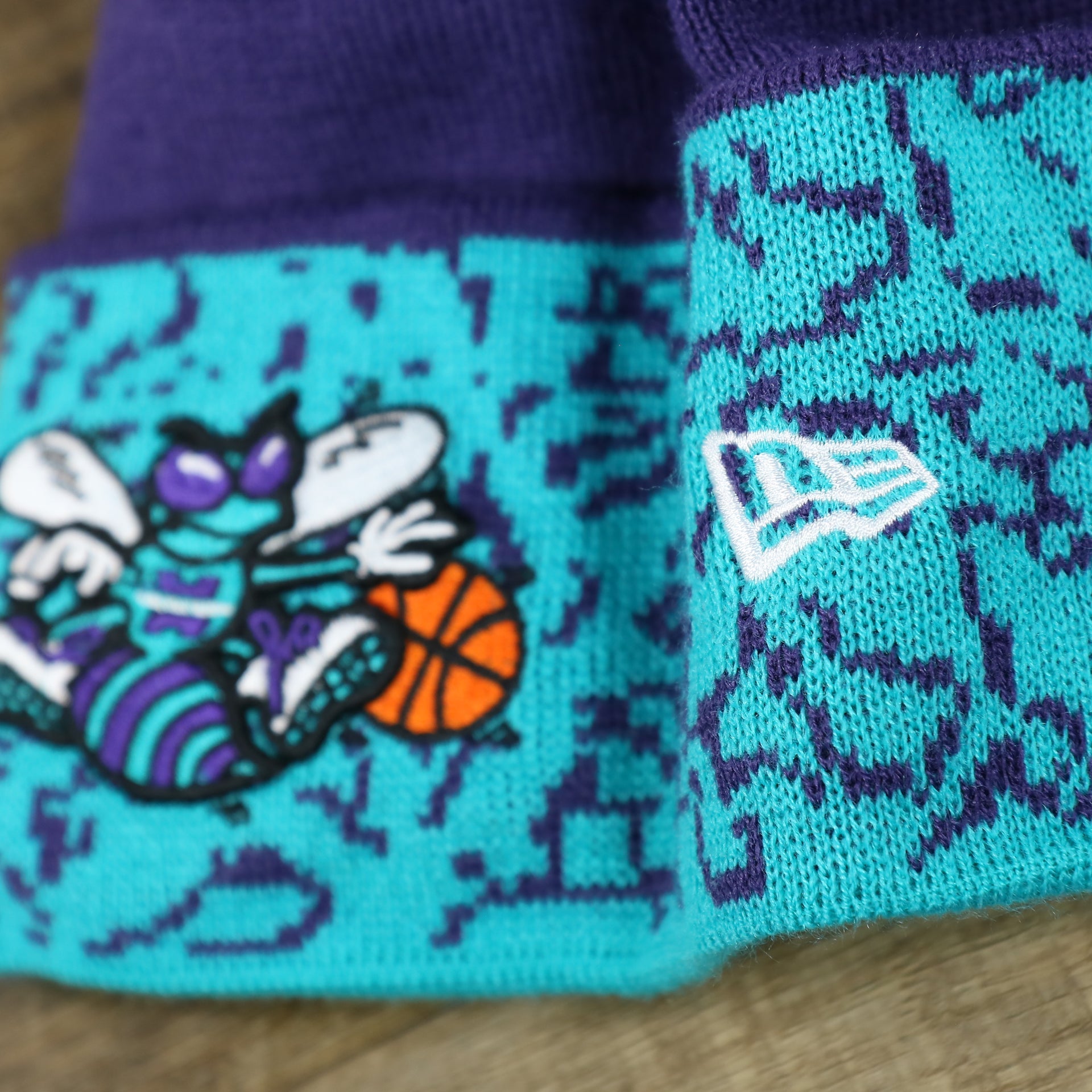 The New Era Logo on the Retro Charlotte Hornets Cuffed Chaos Pom Pom Beanie | Purple And Light Blue Winter Beanie