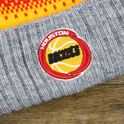 the Houston Rockets Logo on the Retro Houston Rockets Arctic Snowflake Ugly Sweater Pattern Cuffed Beanie With Pom Pom | Yellow, Maroon, and Gray Winter Beanie