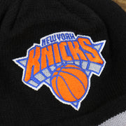 The New York Knicks Logo on the New York Knicks Striped Cuff Black Out Blackout Knit WInter Beanie With Multi Colored Pom Pom | Black Winter Beanie
