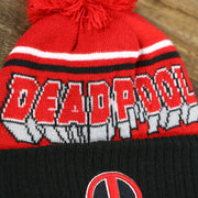 The Deadpool Wordmark on the DC Comics Deadpool Mask Logo Deadpool Wordmark Striped Beanie With Red Pom Pom | Red And Black Winter Beanie