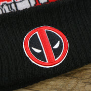 The Deadpool Mask Logo on the DC Comics Deadpool Mask Logo Deadpool Wordmark Striped Beanie With Red Pom Pom | Red And Black Winter Beanie