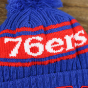 The 76ers Wordmark on the Philadelphia 76ers Knit Wordmark Phila Arch Lettering Join Or Die Snake NBA Draft Striped Beanie | Royal Blue and Red Beanie