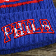 The Phila Join Or Die Arched Wordmark in the Philadelphia 76ers Knit Wordmark Phila Arch Lettering Join Or Die Snake NBA Draft Striped Beanie | Royal Blue and Red Beanie
