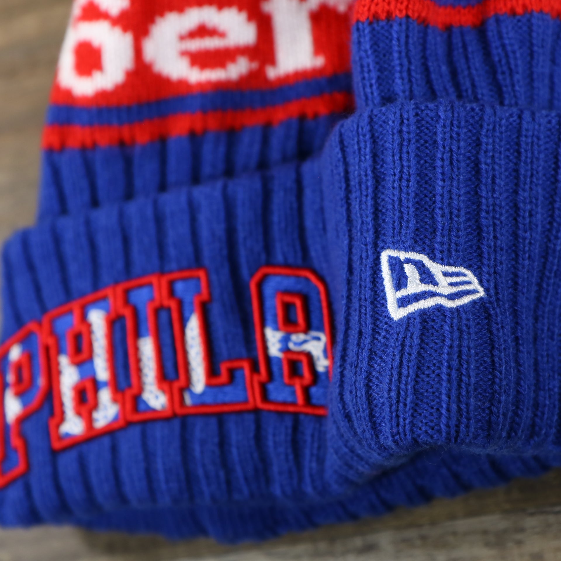 The New Era Logo on the Philadelphia 76ers Knit Wordmark Phila Arch Lettering Join Or Die Snake NBA Draft Striped Beanie | Royal Blue and Red Beanie