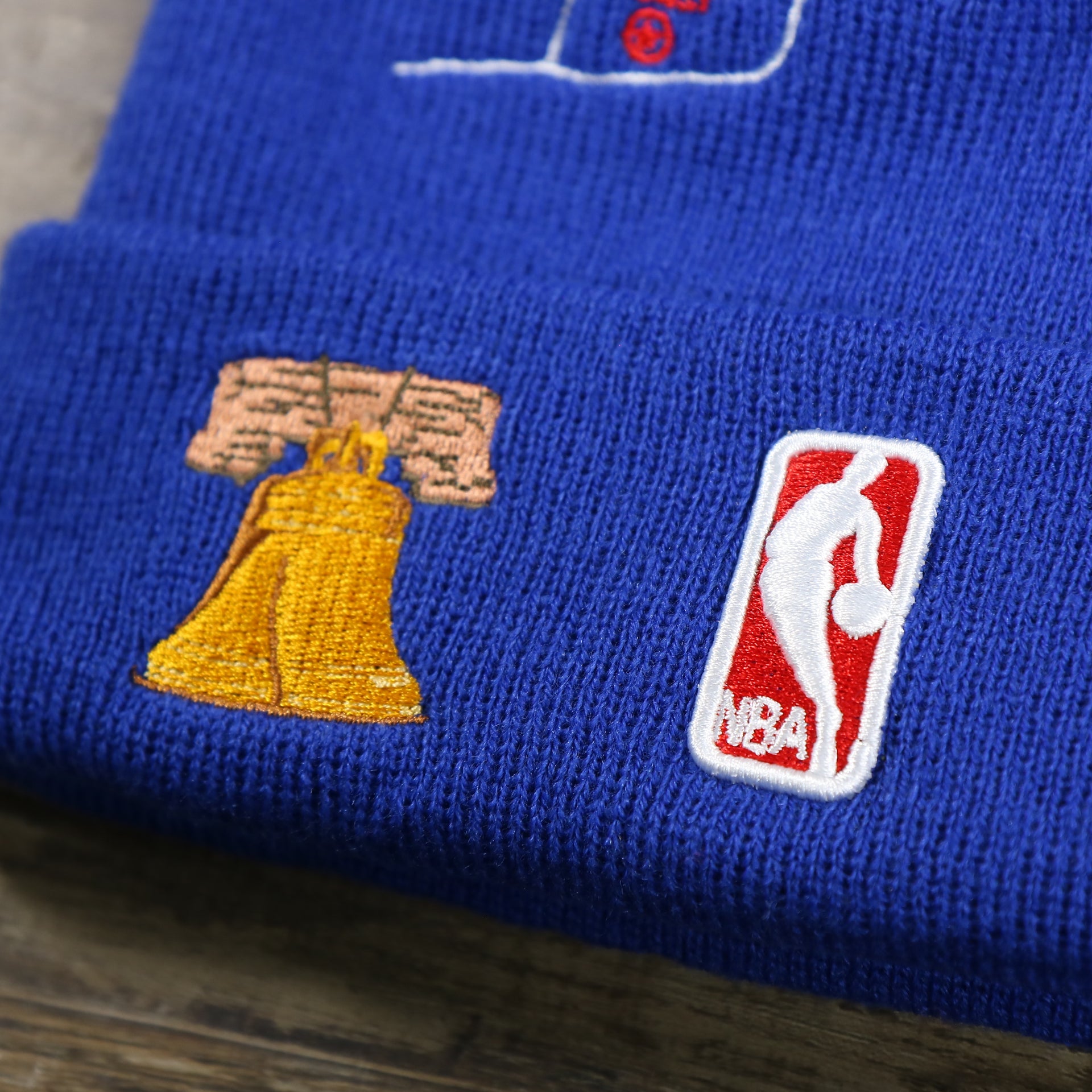 The NBA Jerry West Logo and the Cracker Liberty Bell Patch on the Philadelphia 76ers "City Transit" 59Fifty Fitted Matching All Over Side Patch Beanie