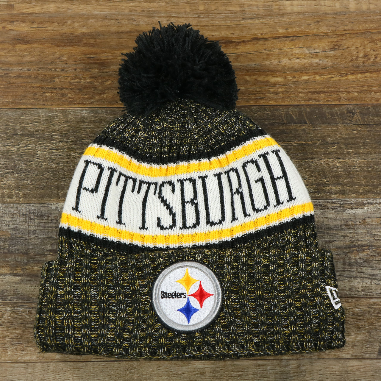 The front of the Pittsburgh Steelers On Field Cold Weather Striped Wordmark Pom Pom Winter Beanie | Black and Yellow Beanie
