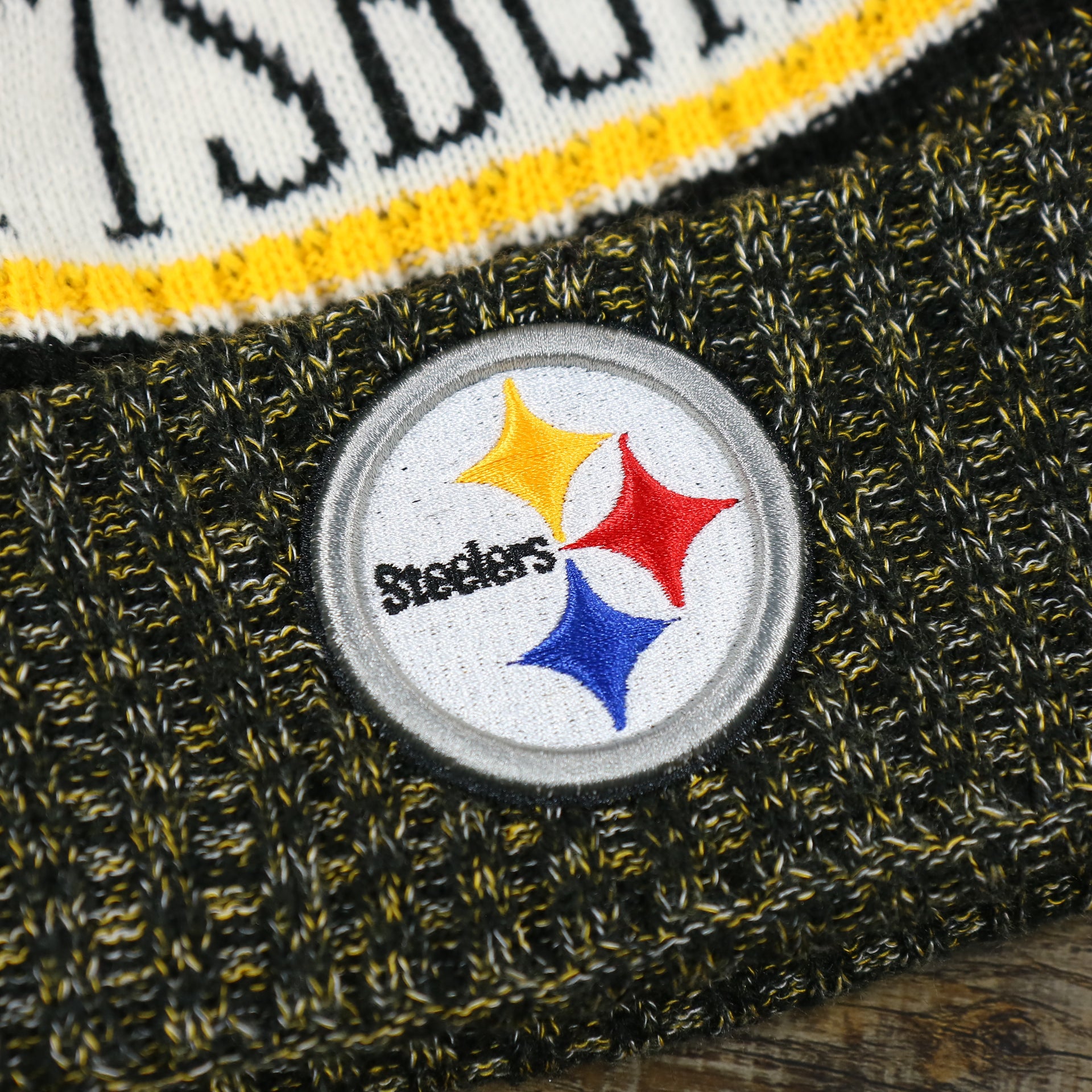 The Steelers Logo on the Pittsburgh Steelers On Field Cold Weather Striped Wordmark Pom Pom Winter Beanie | Black and Yellow Beanie