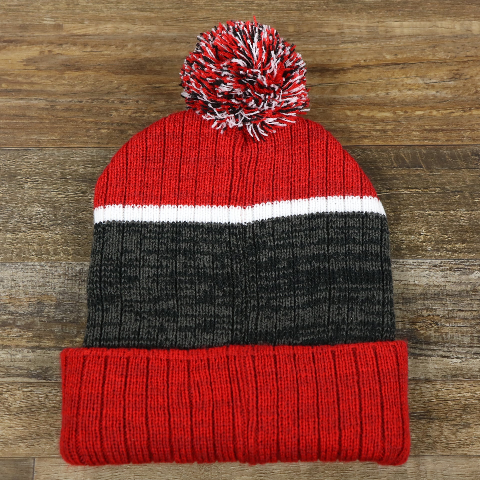 The backside of the New Jersey Devils Cuffed Logo Striped Winter Beanie With Pom Pom | Red and Gray Winter Beanie