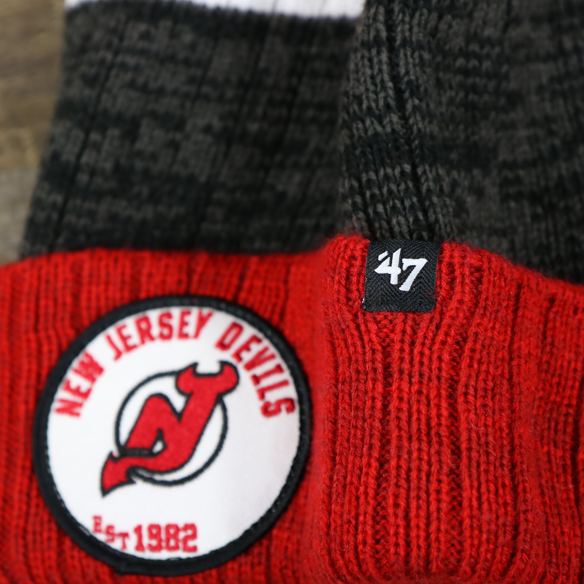 The 47 Brand Tag on the New Jersey Devils Cuffed Logo Striped Winter Beanie With Pom Pom | Red and Gray Winter Beanie