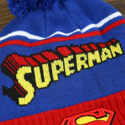 The Superman Wordmark on the DC Comics Superman S-Shield Logo Superman Wordmark Striped Beanie With Blue Pom Pom | Blue And Red Winter Beanie