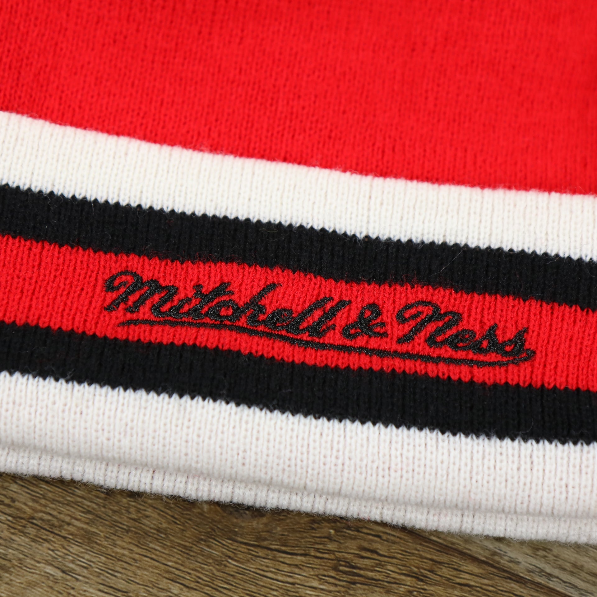 The Mitchell And Ness Script Logo on the Chicago Bulls Striped Cuff Pom Pom Winter Beanie | Red Winter Beanie