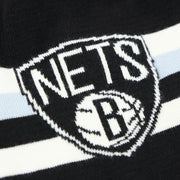 The Brooklyn nets Logo on the Brooklyn Nets Cuffless Striped Winter Beanie With Pom Pom | Black, White, And Gray Beanie