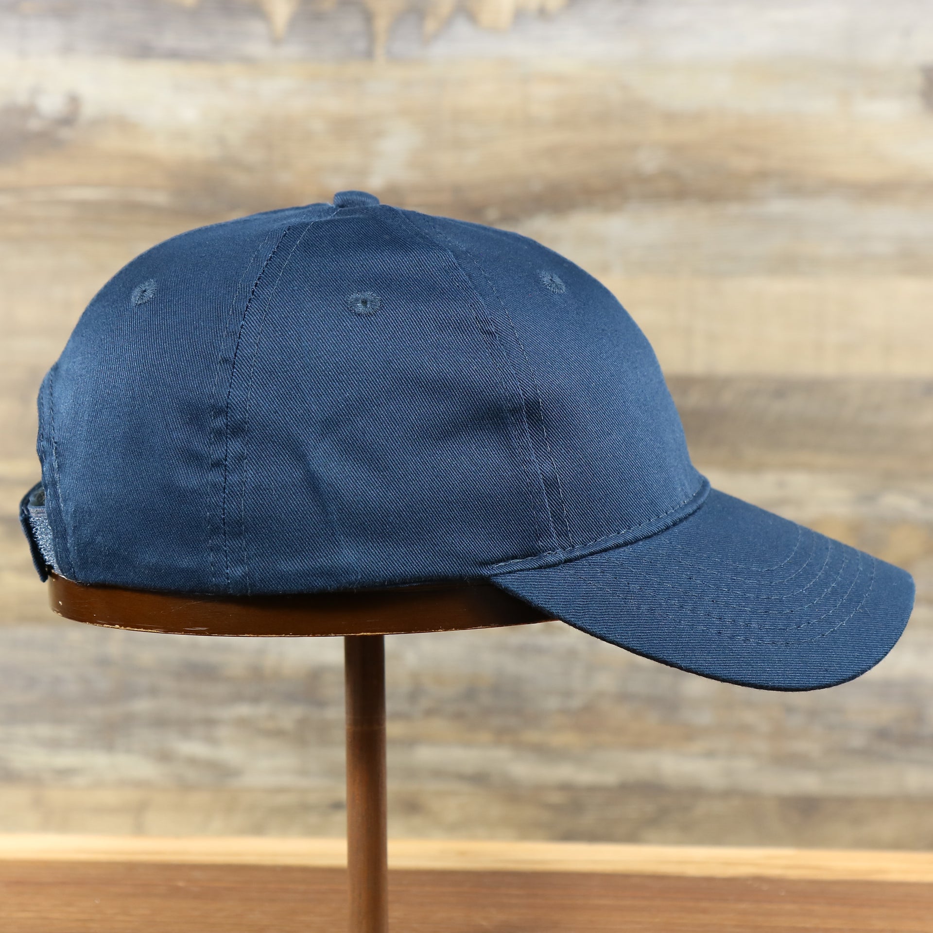 The wearer's right on the Youth Navy Blue Flat Brim Blank Baseball Hat | Kid’s Dark Blue Dad Hat