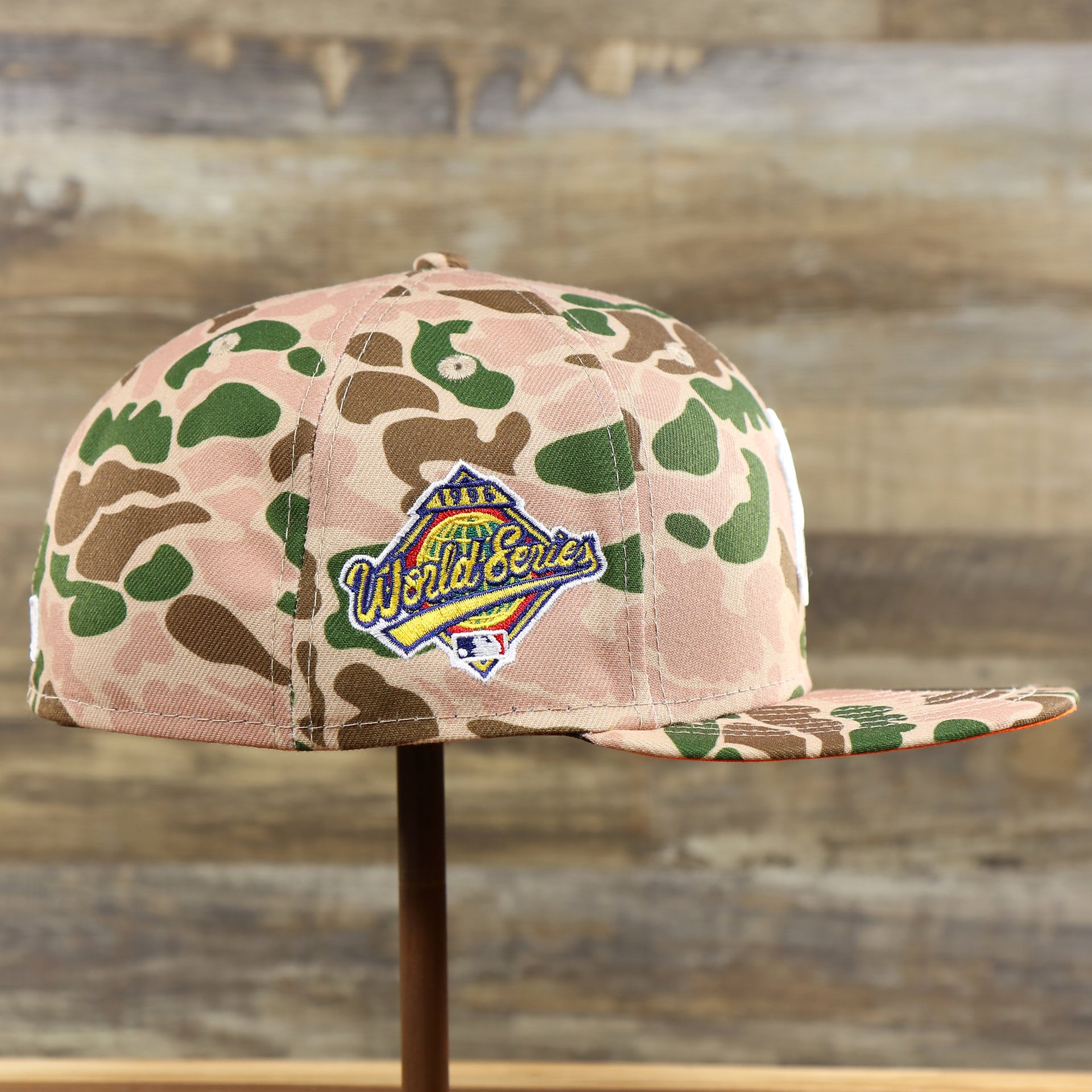The wearer's left of the New York Yankees Duck Camo Neon Orange Undervisor World Series Side Patch Fitted Cap | Camo Tan 59Fifty Cap