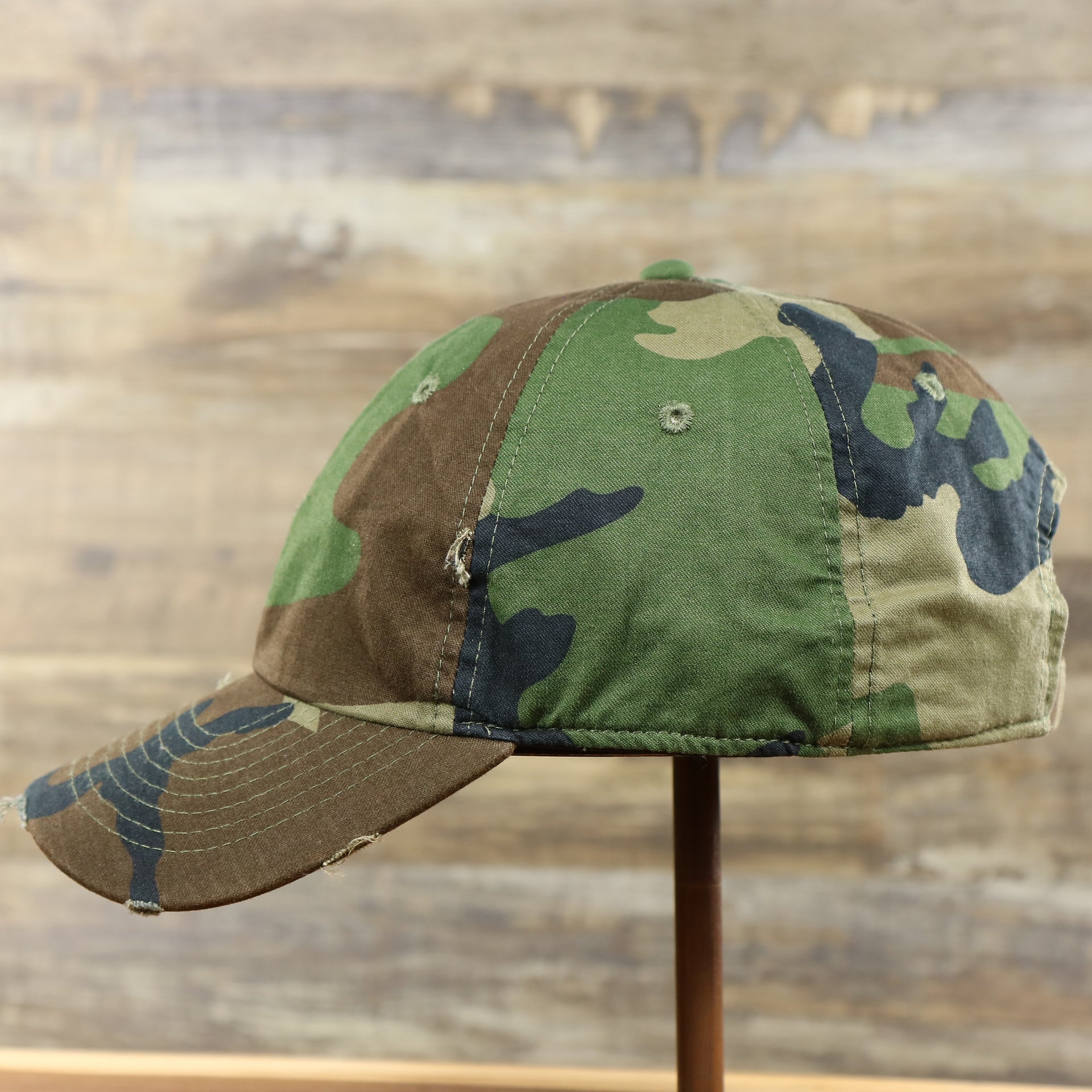 The wearer's left of the Forest Camo Bent Brim Distressed Blank Baseball Hat | Dark Green Dad Hat