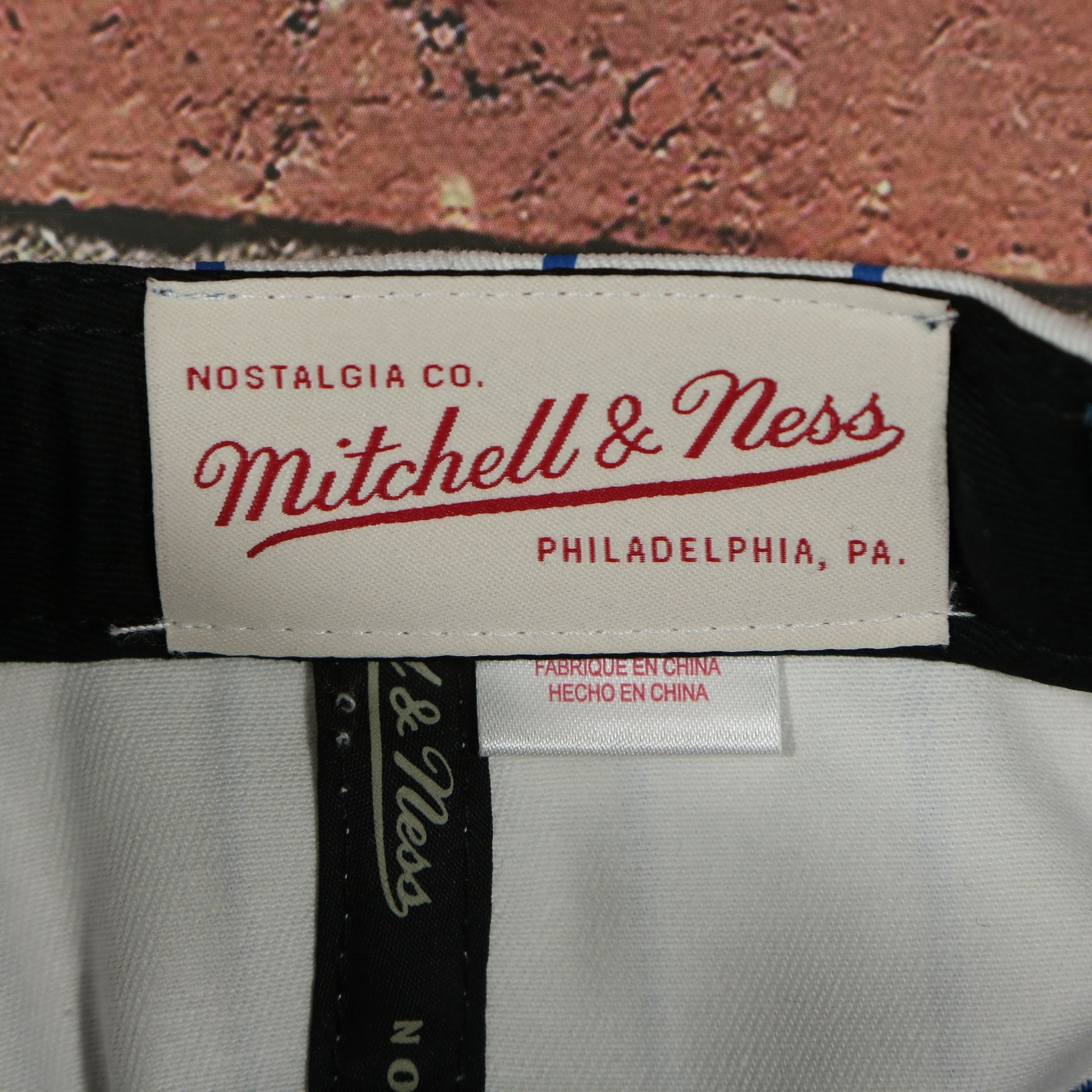 mitchell and ness label on the Philadelphia 76ers Vintage Pinstripe Baseball Hat | Retro Mitchell and Ness White Pinstripe Snapback Hat