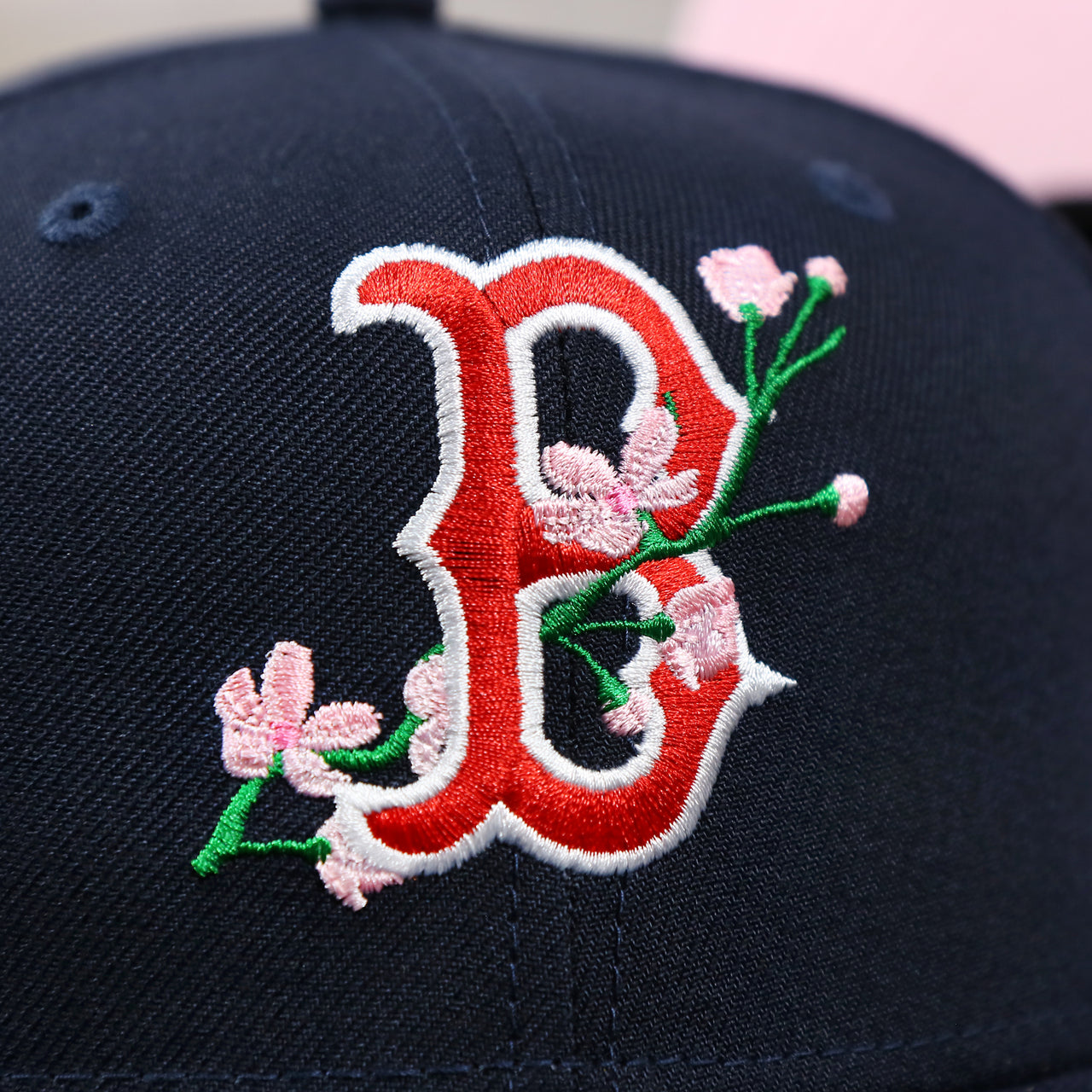 The Red Sox Sakura Logo on the Boston Red Sox Pink Undervisor Sakura Tree Embroidered 59Fifty Fitted Cap | Navy Blue 59Fifty Cap