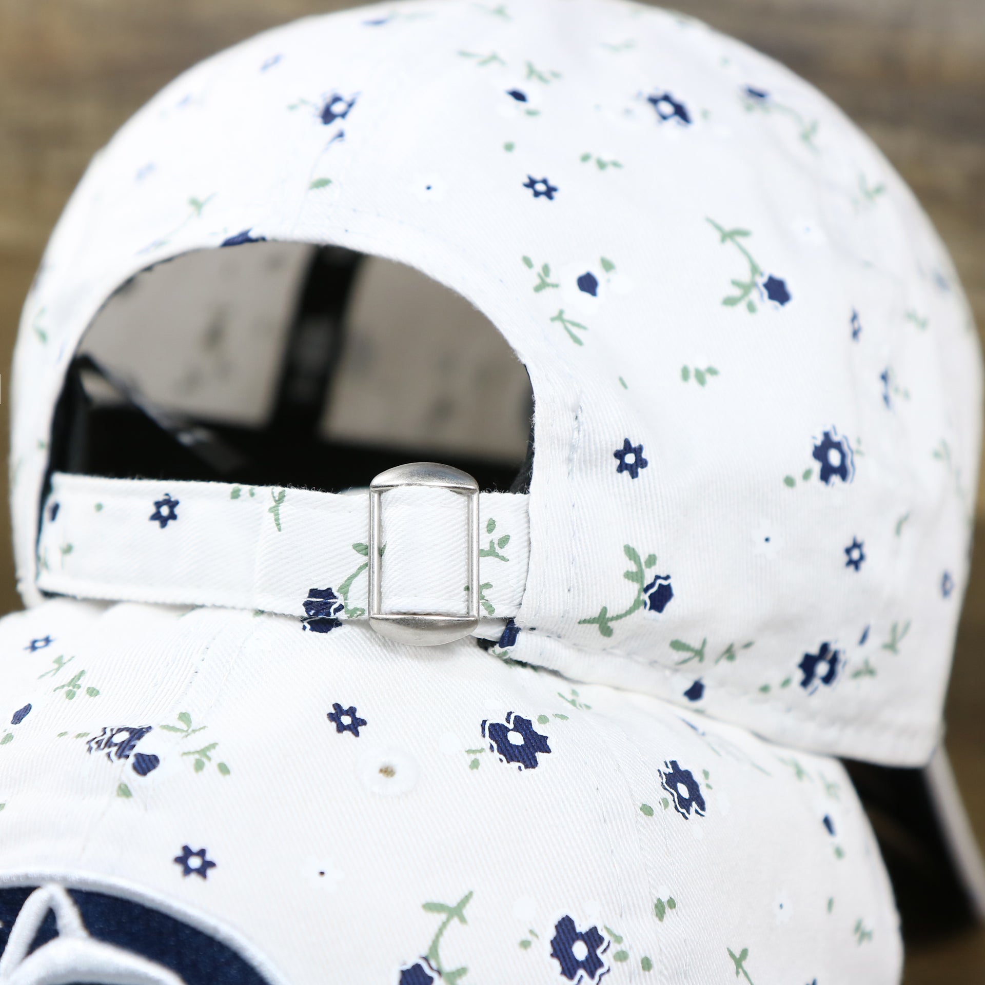 The adjustable strap with metallic buckle on the Women’s Penn State Nittany Lions All Over Micro Floral Print 9Twenty Dad hat | White 9Twenty Hat