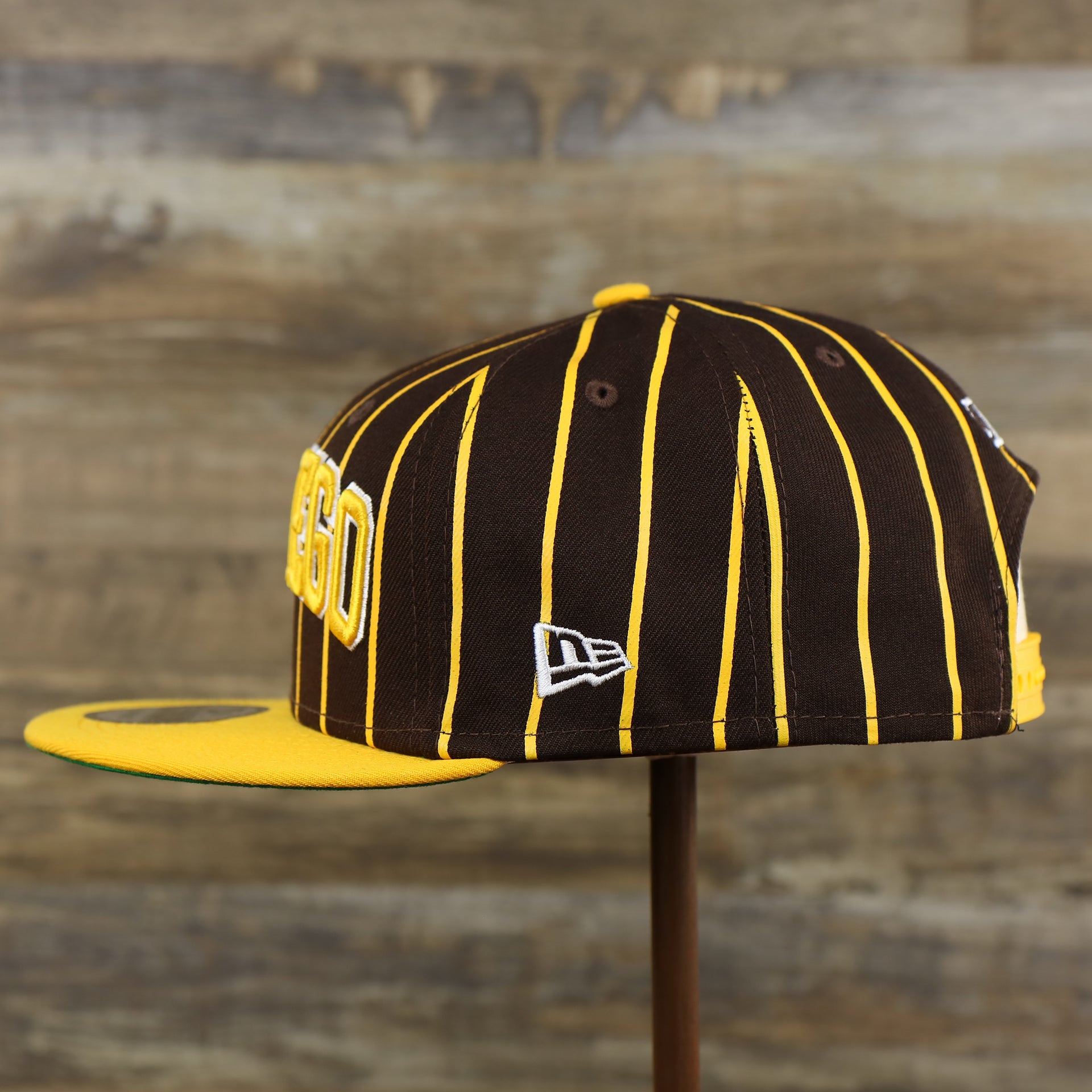 The wearer's left of the San Diego Padres City Arch Pinstriped 9Fifty Snapback Cap | Brown 9Fifty Cap
