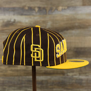 The wearer's right on the San Diego Padres City Arch Pinstriped 9Fifty Snapback Cap | Brown 9Fifty Cap