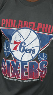 76ers logo on the Philadelphia 76ers NBA Hardwood Classics Vintage Cracked Tee | Charcoal Grey T-shirt