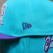 The New Era logo on the Charlotte Hornets Team Script Gray Bottom 9Fifty Snapback | Turquoise and Purple Snap Cap