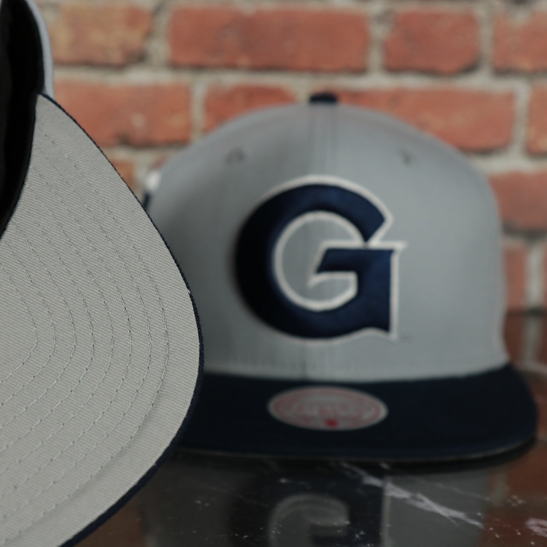 grey under visor on the Georgetown Hoyas NCAA Jumbotron "Hoyas" Ripped Wordmark side patch Grey Bottom Grey/Navy Snapback hat | Mitchell and Ness Two Tone Snap Cap