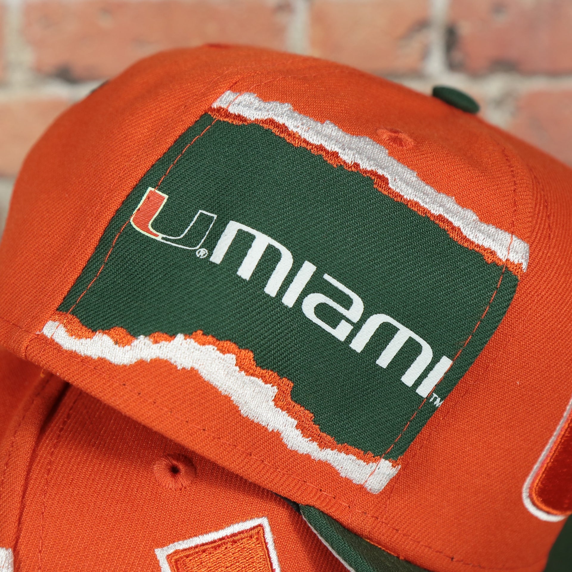 hurricanes jumbotron side patch on the Miami Hurricanes NCAA Jumbotron "U Miami" Ripped Wordmark side patch Grey Bottom Orange/Green Snapback hat | Mitchell and Ness Two Tone Snap Cap