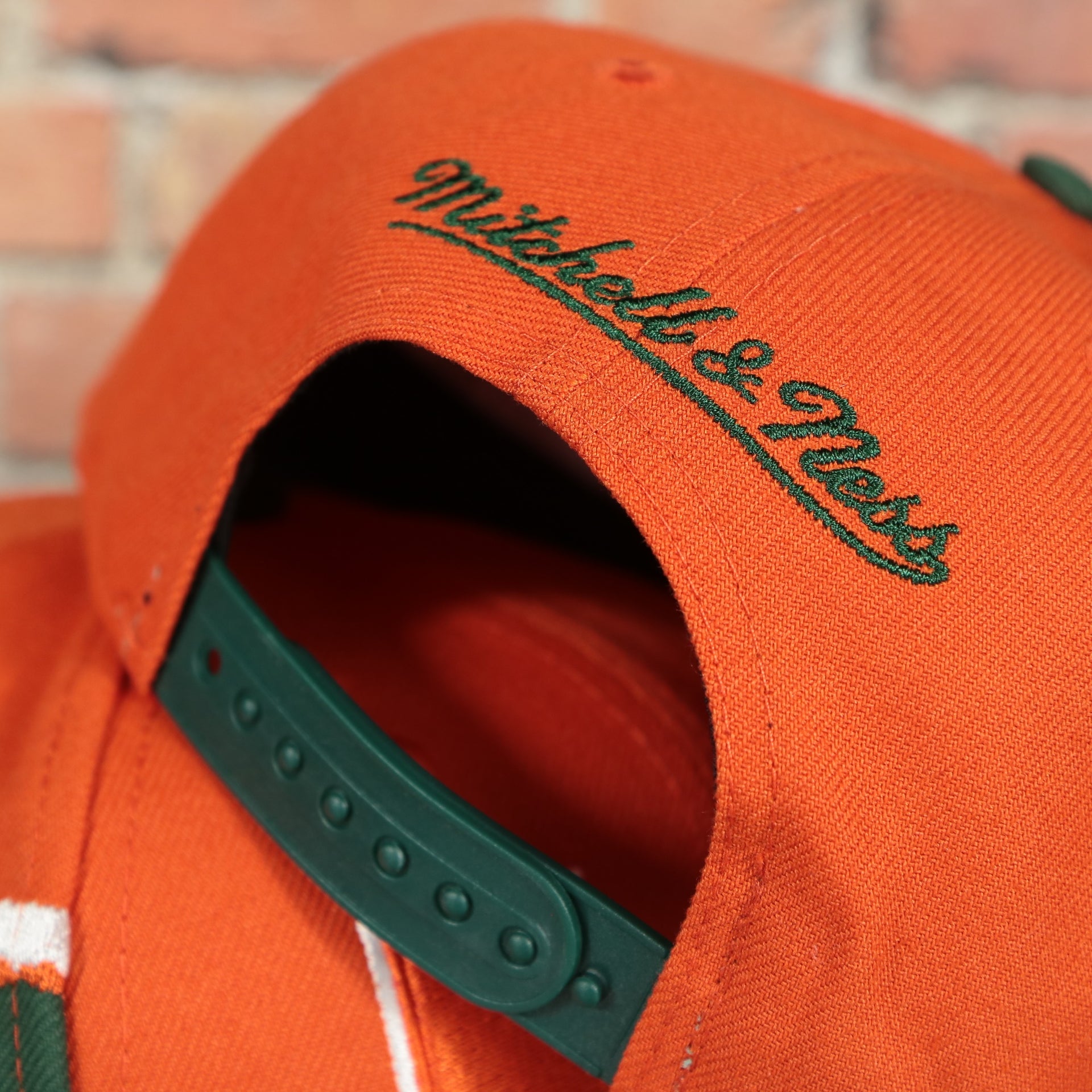 mitchell and ness logo on the Miami Hurricanes NCAA Jumbotron "U Miami" Ripped Wordmark side patch Grey Bottom Orange/Green Snapback hat | Mitchell and Ness Two Tone Snap Cap