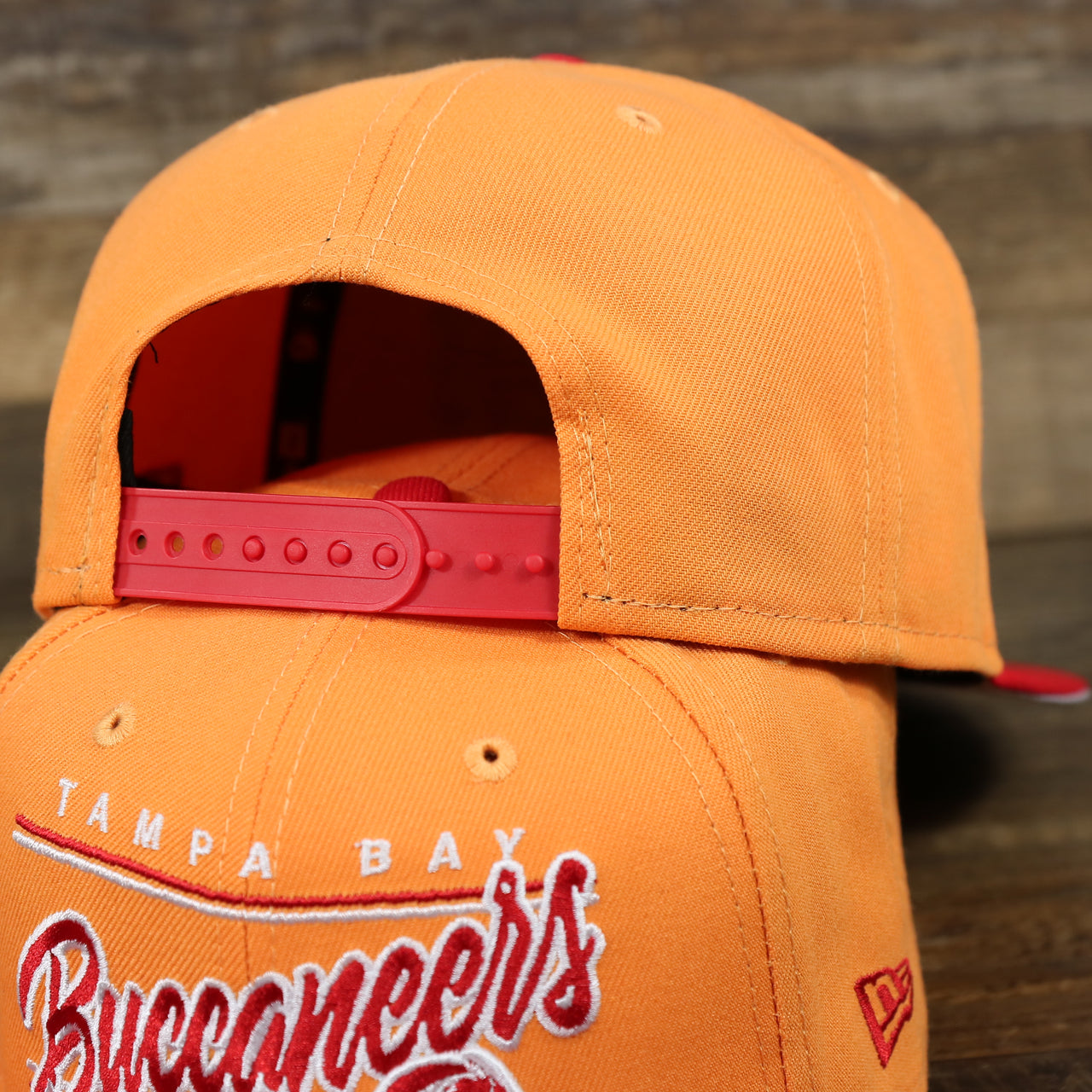 The backside of the Tampa Bay Buccaneers Team Script Gray Bottom 9Fifty Snapback | Orange And Red Snap Cap