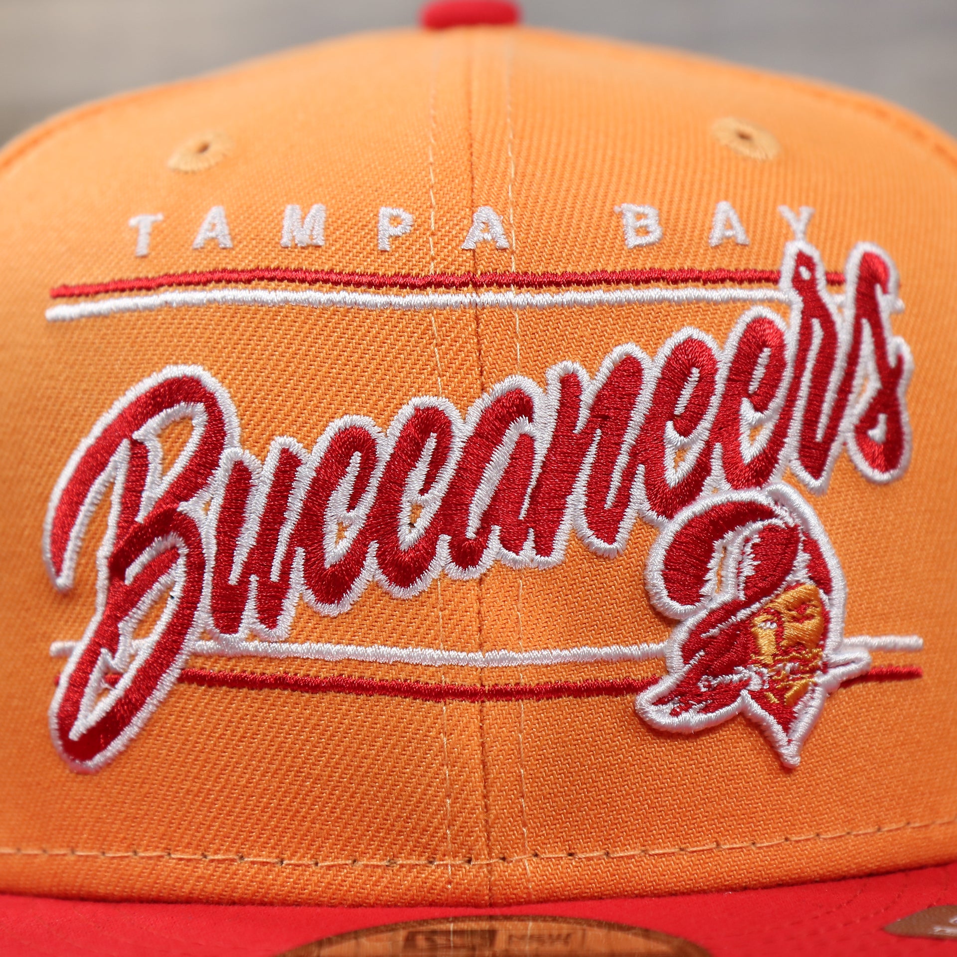 The Tampa Bay Buccaneers Team Script on the Tampa Bay Buccaneers Team Script Gray Bottom 9Fifty Snapback | Orange And Red Snap Cap