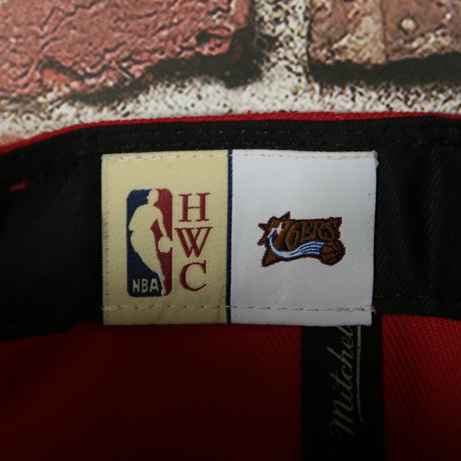 HWC label on the Philadelphia 76ers Hardwood Classics Jumbotron "76ers" Ripped Wordmark side patch Grey Bottom Red/Black Snapback hat | Mitchell and Ness Two Tone Snap Cap