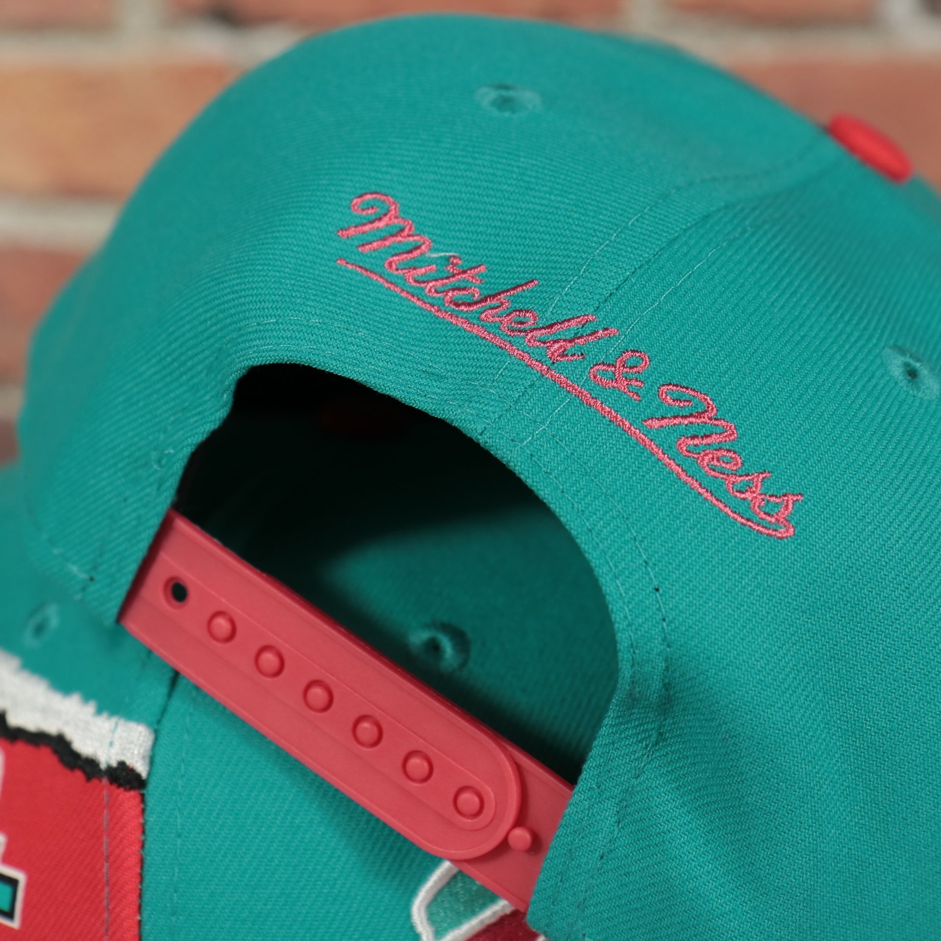 mitchell and ness logo on the San Antonio Spurs Hardwood Classics Jumbotron Spurs Ripped Logo side patch Grey Bottom Teal/Red Snapback hat | Mitchell and Ness Two Tone Snap Cap