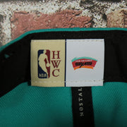 HWC label on the San Antonio Spurs Hardwood Classics Jumbotron Spurs Ripped Logo side patch Grey Bottom Teal/Red Snapback hat | Mitchell and Ness Two Tone Snap Cap