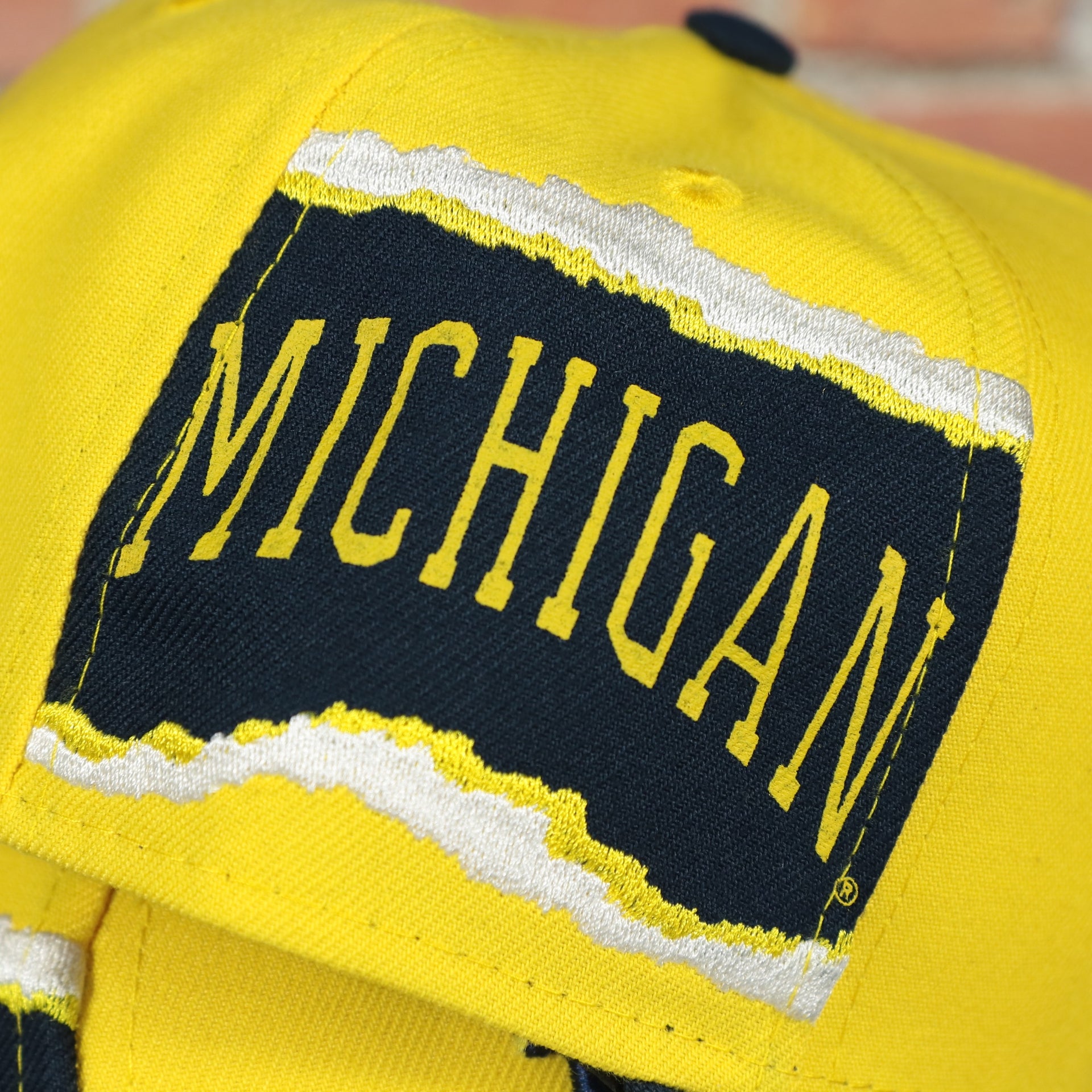 wolverines jumbotron side patch on the Michigan Wolverines NCAA Jumbotron "Michigan" Ripped Wordmark side patch Grey Bottom Yellow/Navy Snapback hat | Mitchell and Ness Two Tone Snap Cap