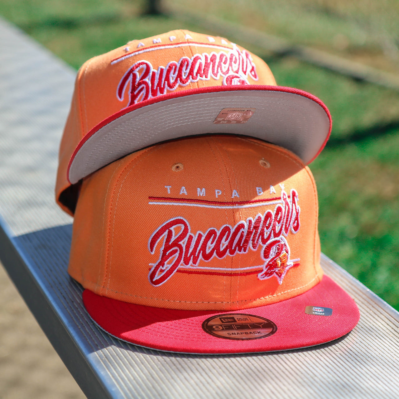 The front of the Tampa Bay Buccaneers Team Script Gray Bottom 9Fifty Snapback | Orange And Red Snap Cap
