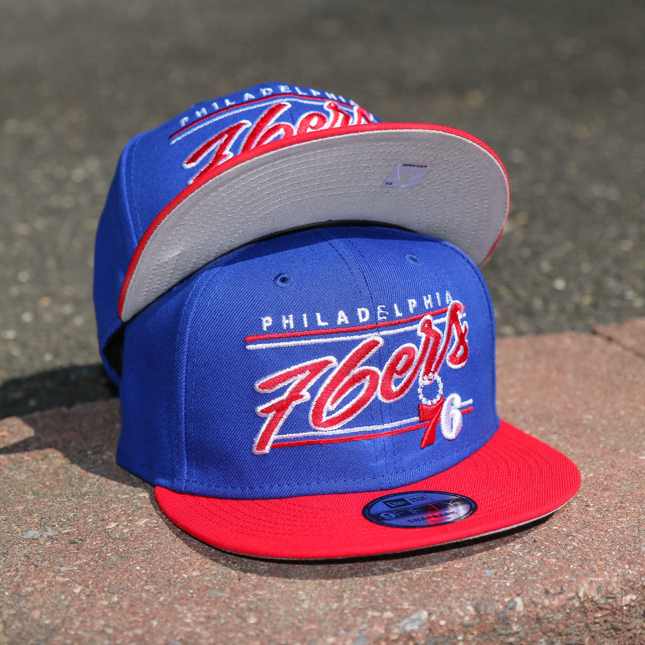 The front of the Philadelphia 76ers Team Script Gray Bottom 9Fifty Snapback | Royal Blue And Red Snap Cap