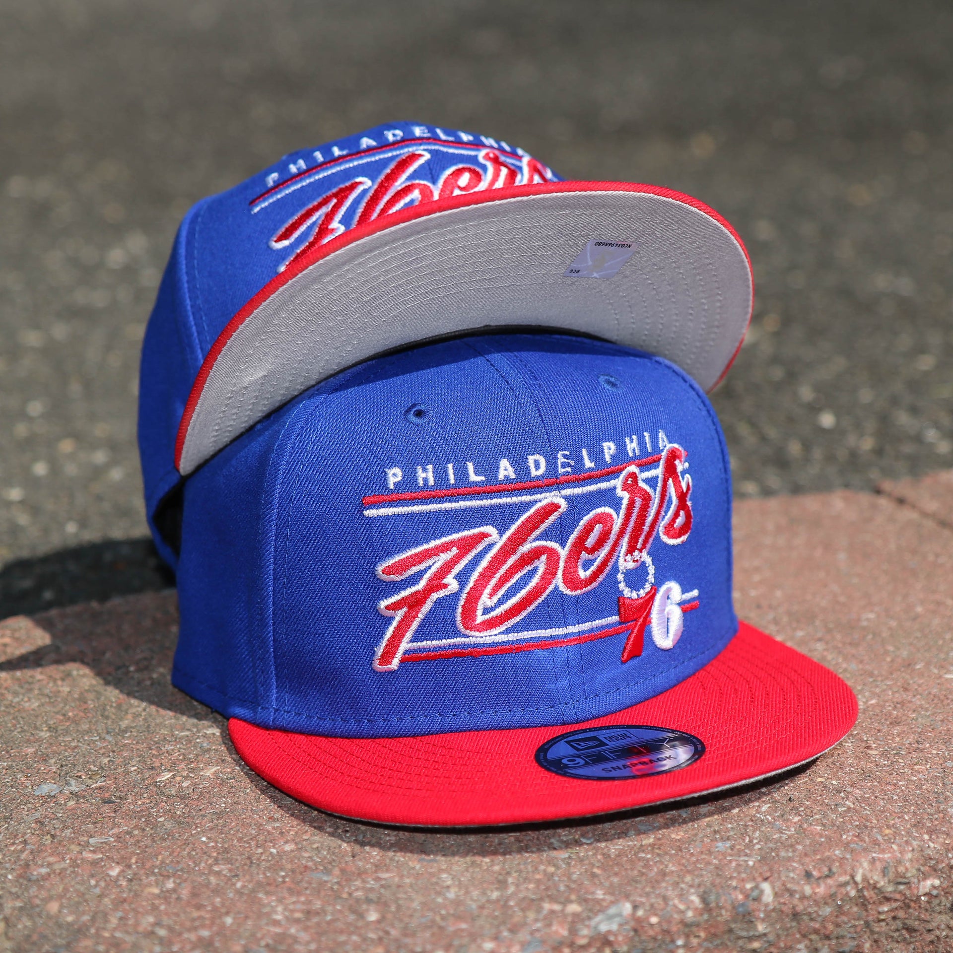 The front of the Philadelphia 76ers Team Script Gray Bottom 9Fifty Snapback | Royal Blue And Red Snap Cap