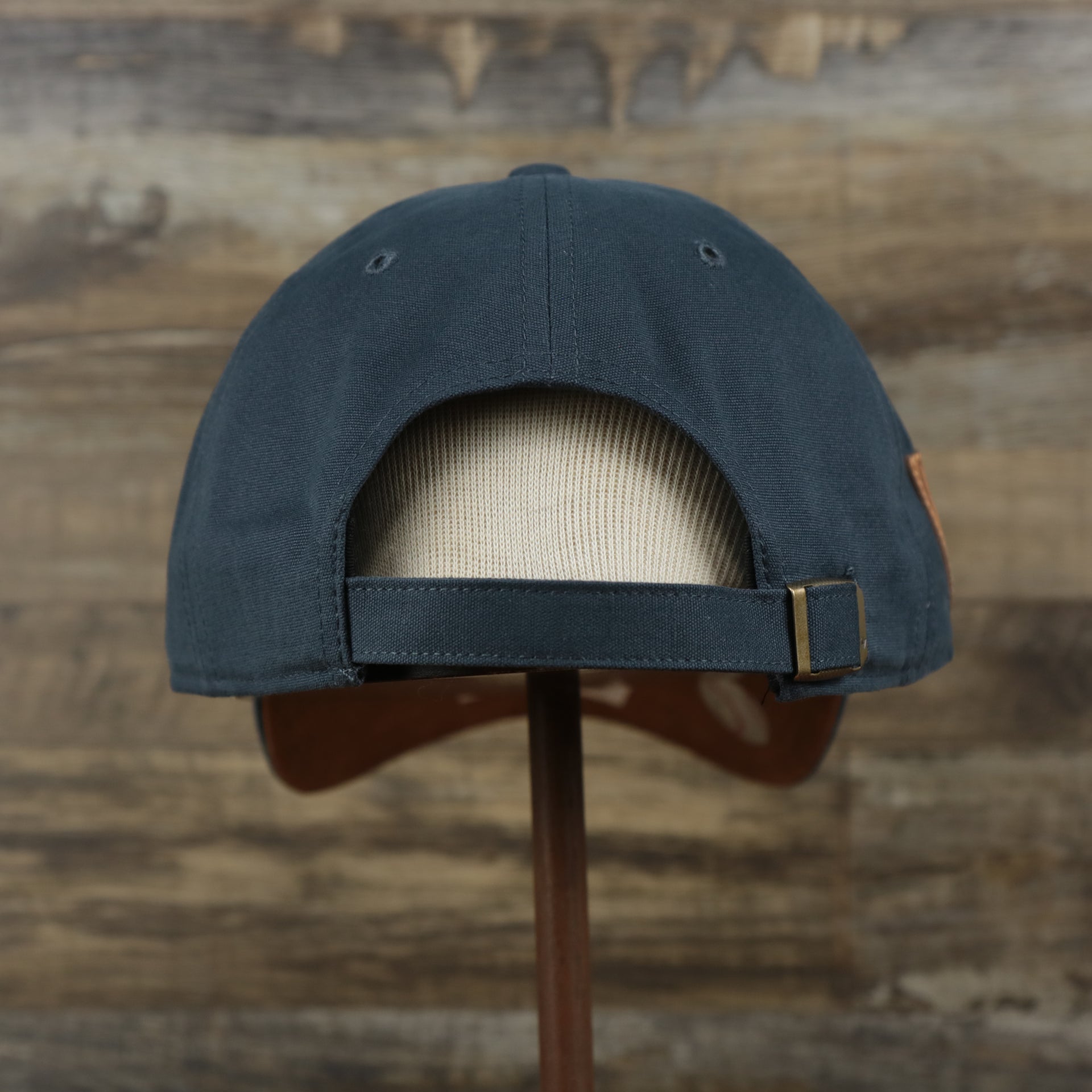 The backside of the Cooperstown Houston Astros Cooperstown Collection Side Patch Leather Brown Undervisor Dad Hat | Vintage Navy Dad Hat