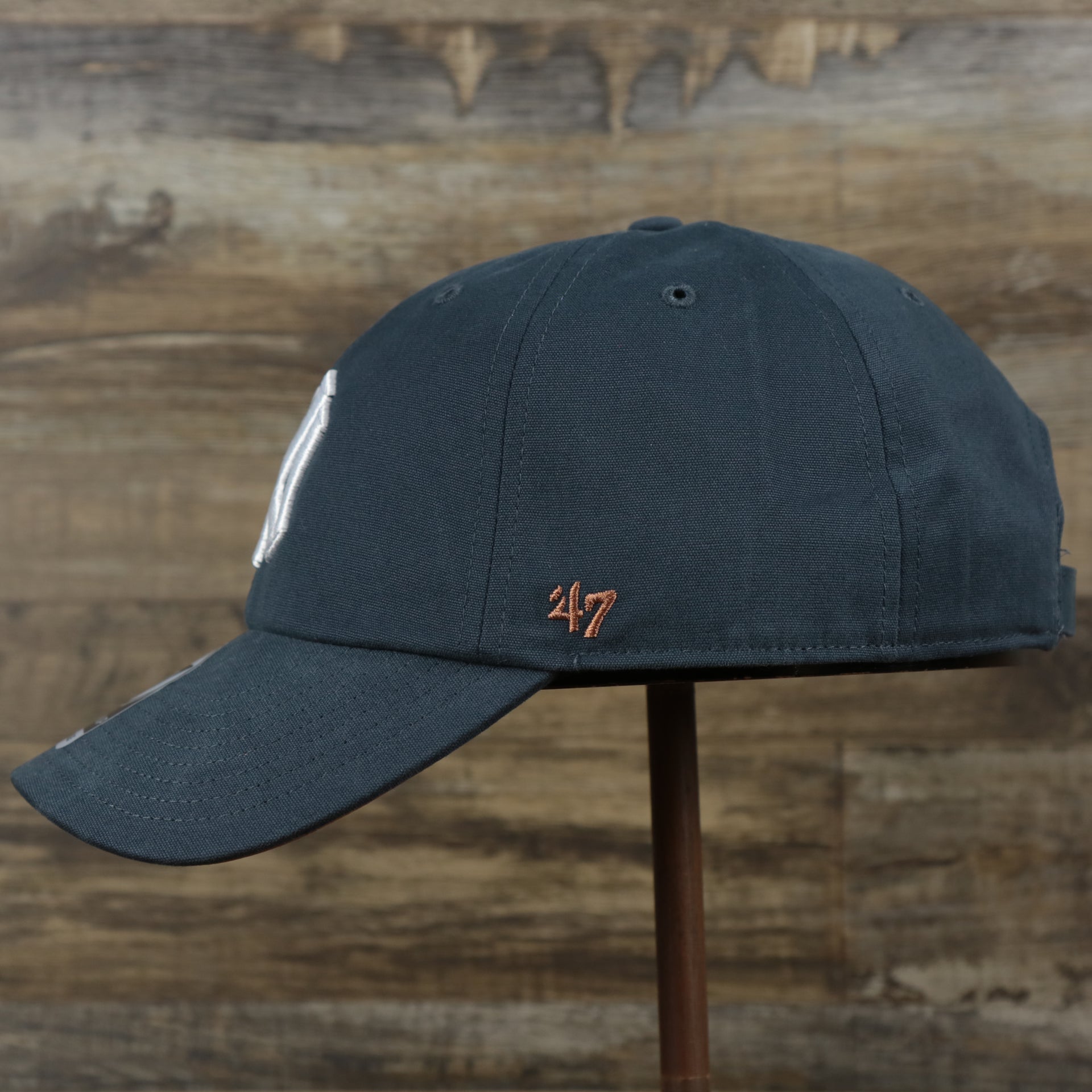 The wearer's left on the Cooperstown New York Yankees Cooperstown Collection Side Patch Leather Brown Undervisor Dad Hat | Vintage Navy Dad Hat